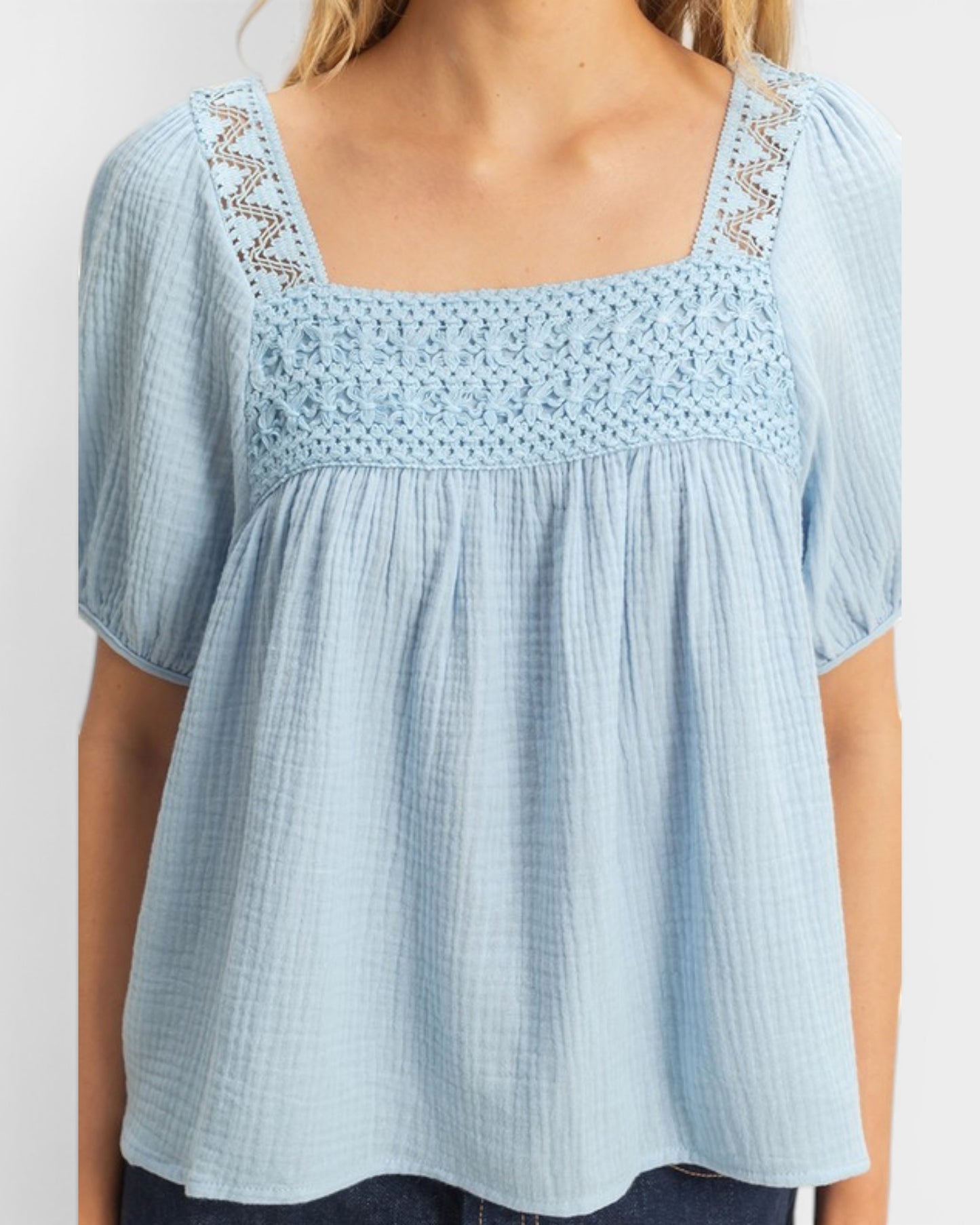 Light blue blouse with lace details on a white background