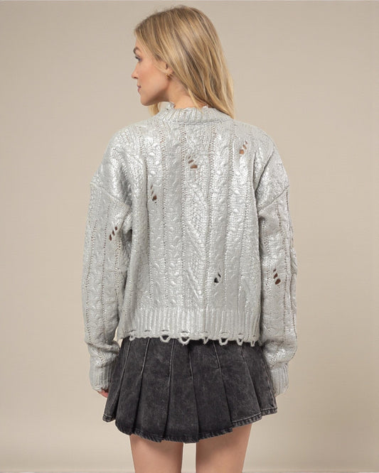 Woman wearing a silver sequin jacket and black pleated skirt on a beige background