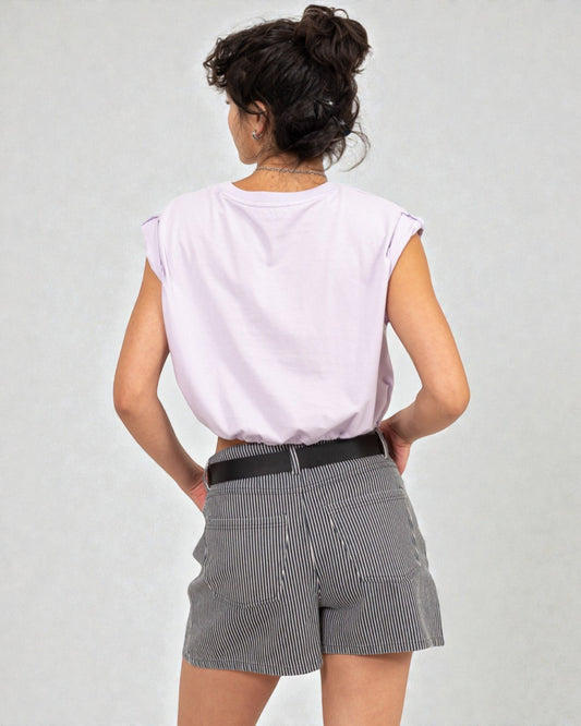 Person wearing a light purple top and gray shorts on a plain background