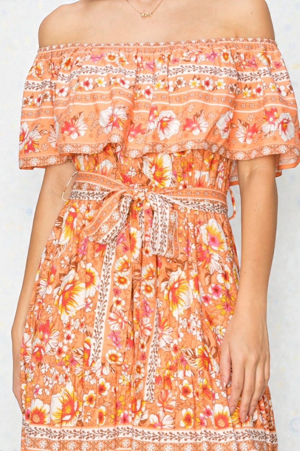 Floral off-shoulder dress with a belt on a plain background