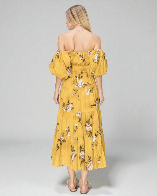 Woman wearing a yellow floral off-shoulder dress on a gray background