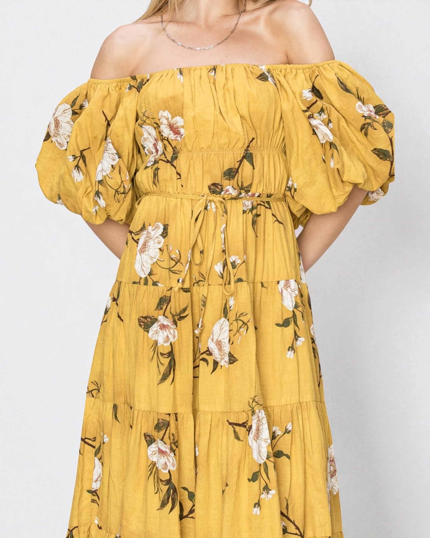 Yellow floral off-shoulder dress on a plain background