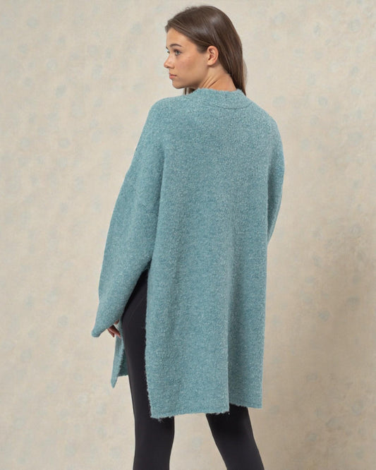 Woman wearing a teal poncho against a beige background