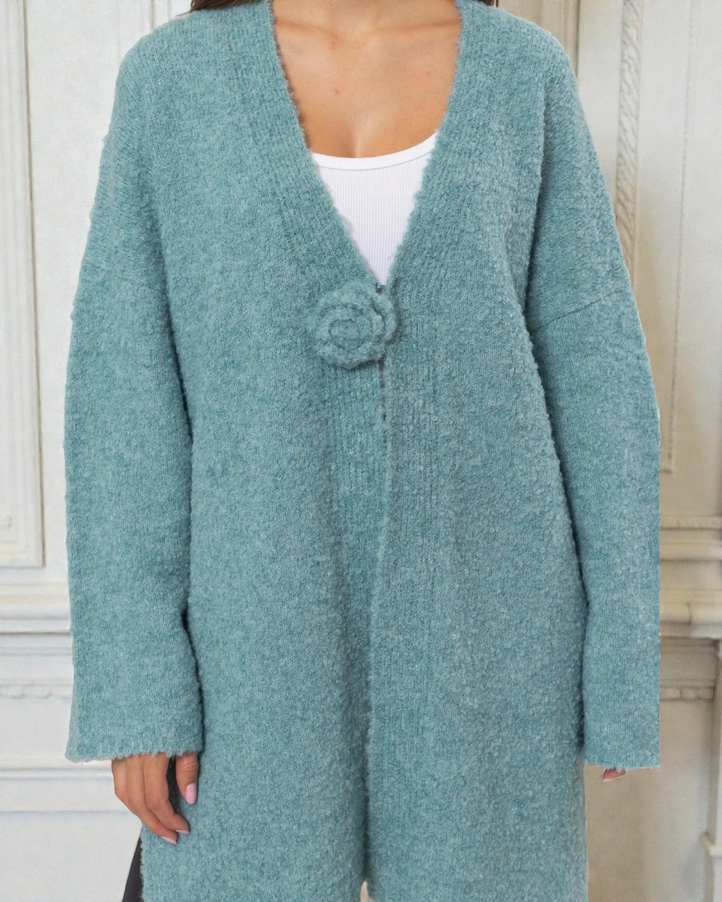 Teal cardigan worn by a person with a white background