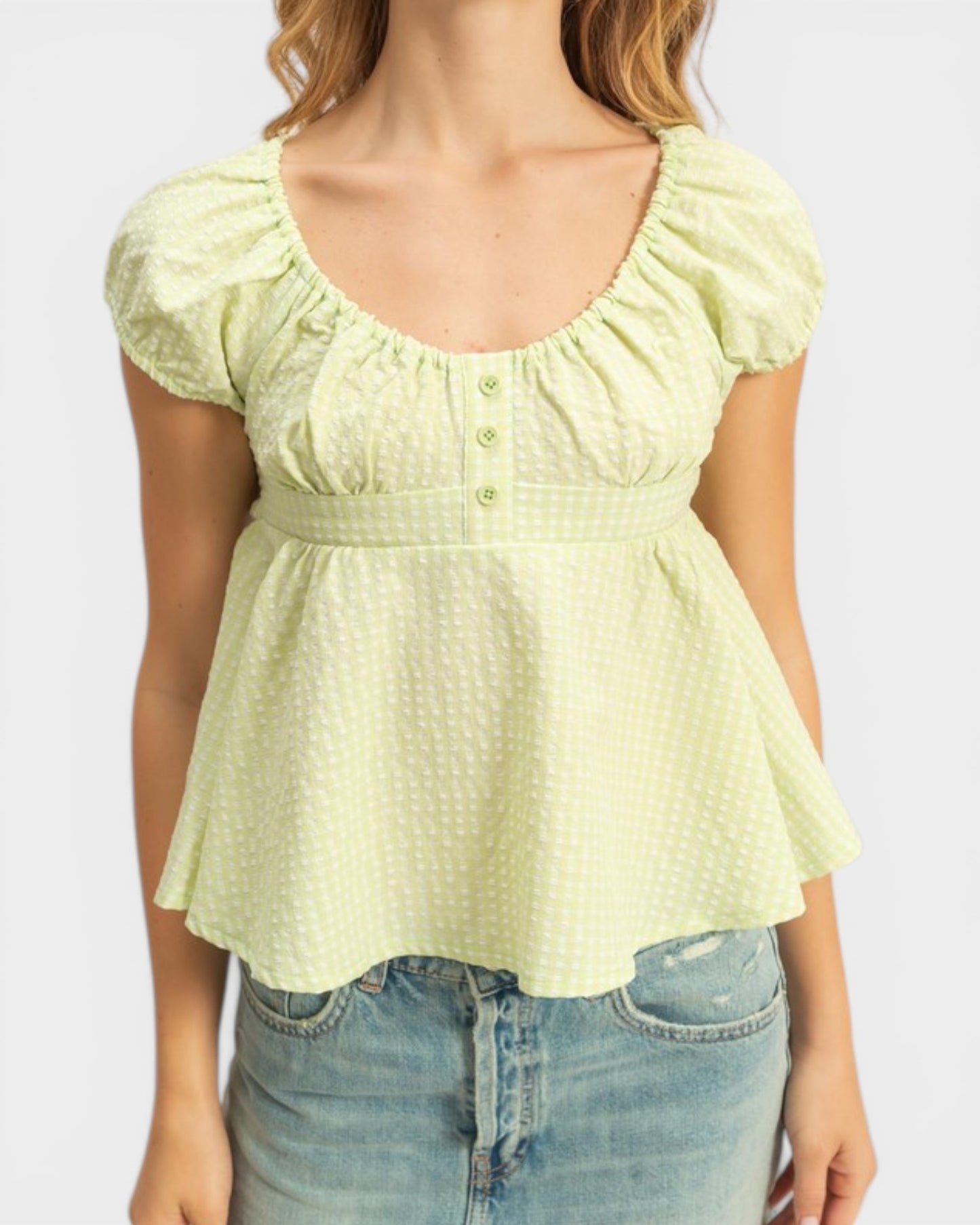 Light green blouse with ruffled sleeves worn by a person on a white background