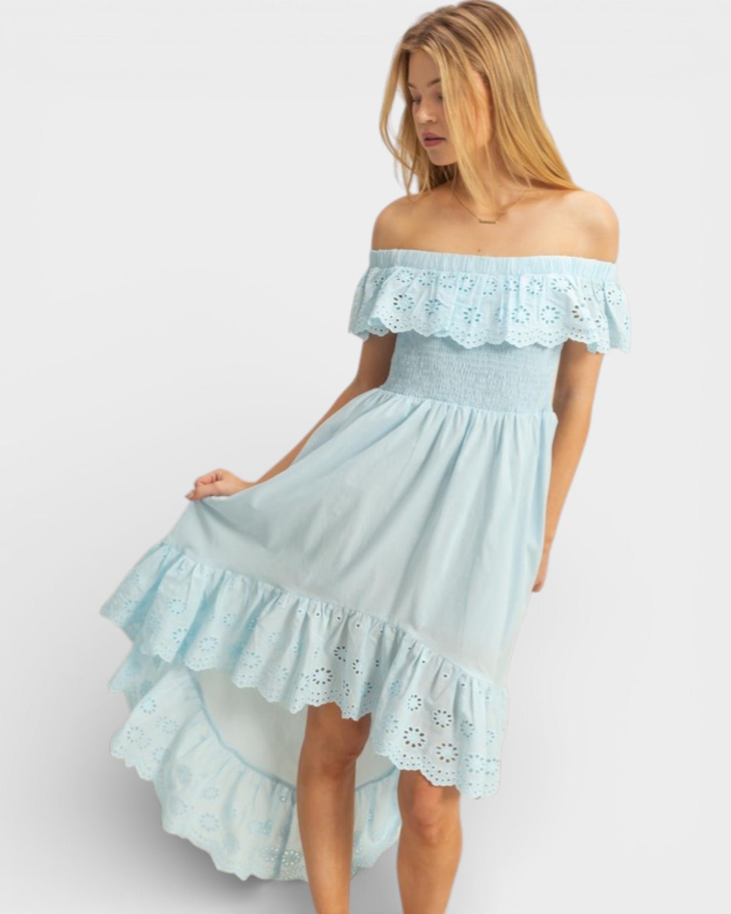 Woman wearing a light blue off-shoulder dress with floral details on a white background