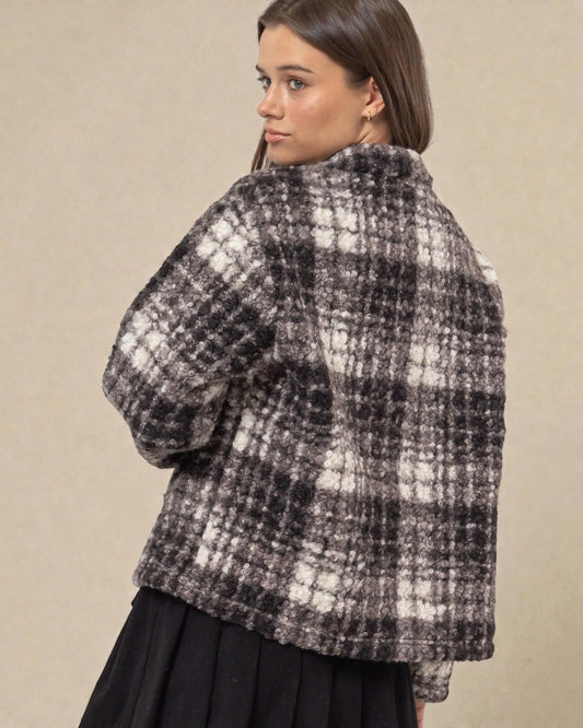 Woman wearing a black and white checkered jacket on a beige background