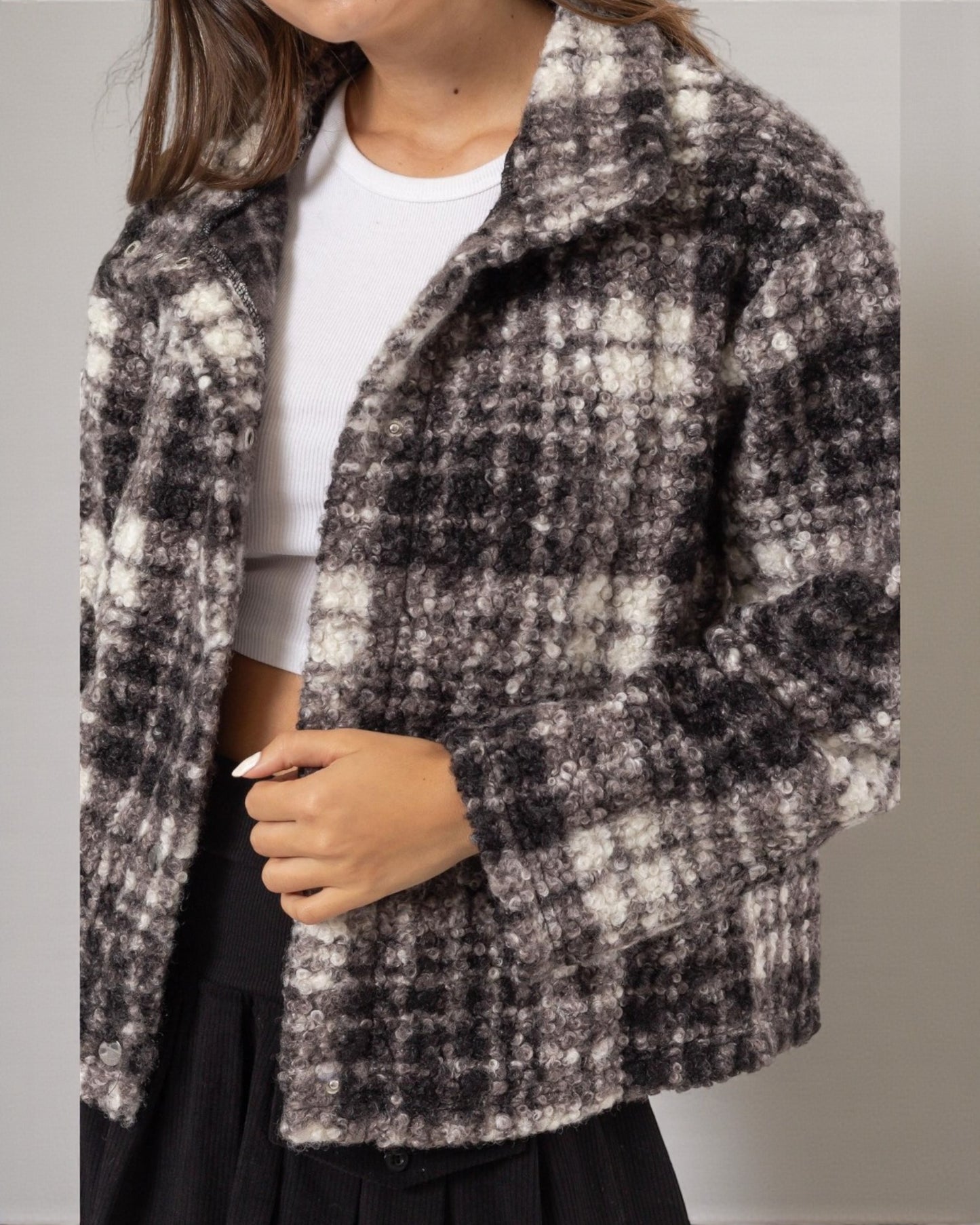 Person wearing a checkered coat with a neutral background