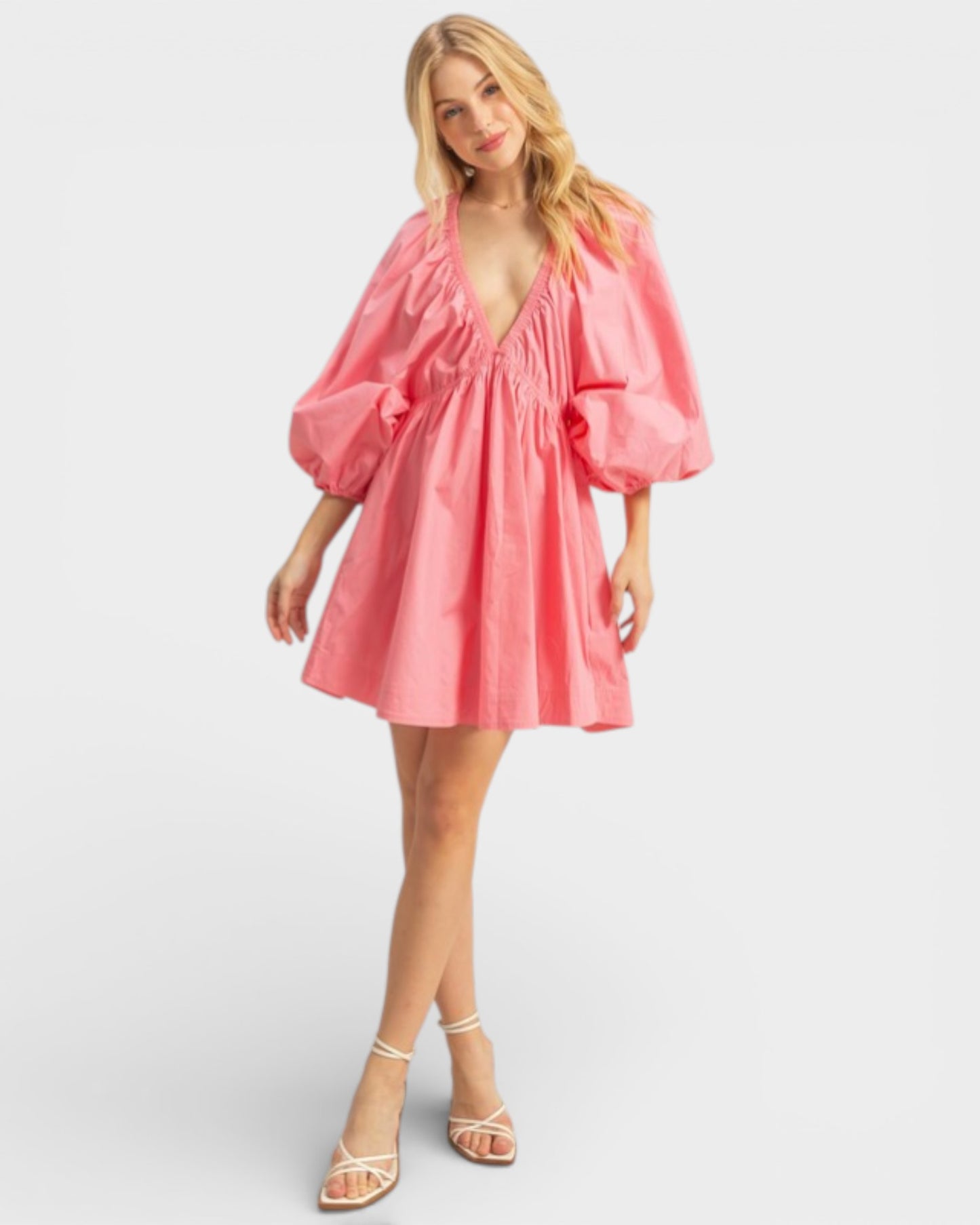 Woman wearing a pink dress with puff sleeves on a white background