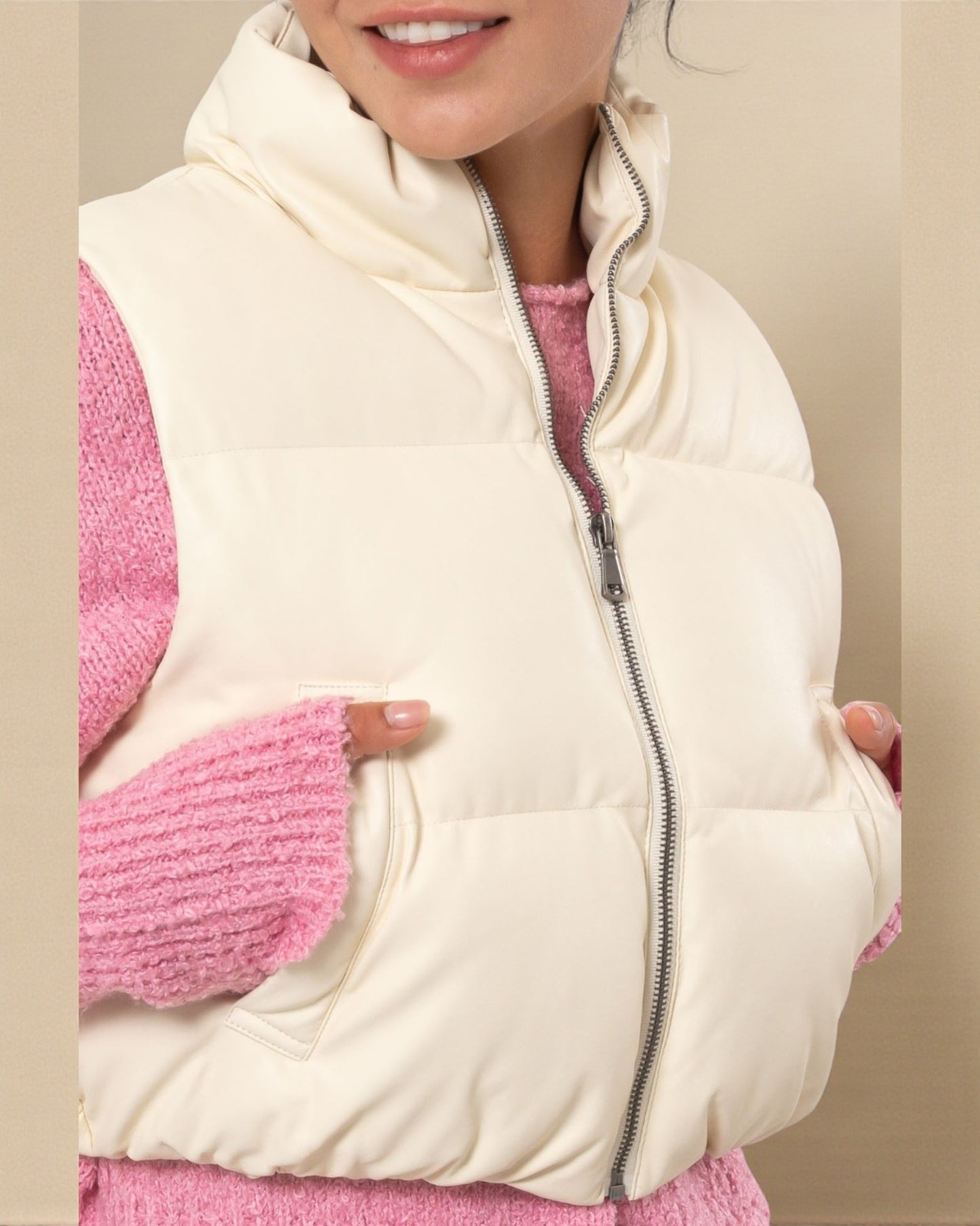 Person wearing a cream-colored puffer vest over a pink outfit.