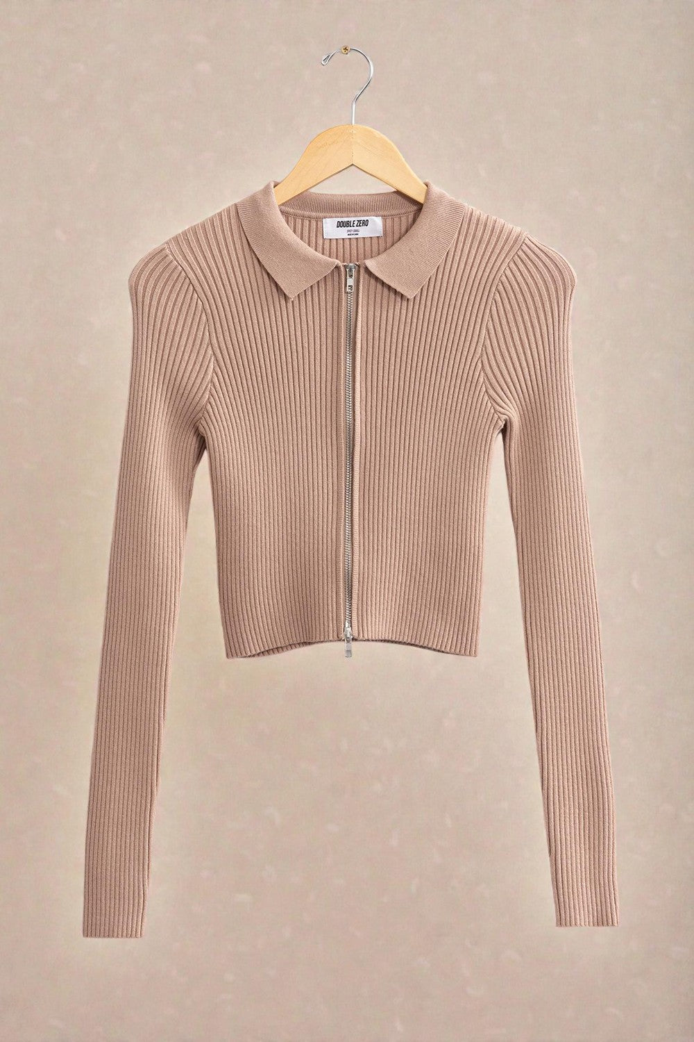 Beige ribbed zip-up sweater on a beige background