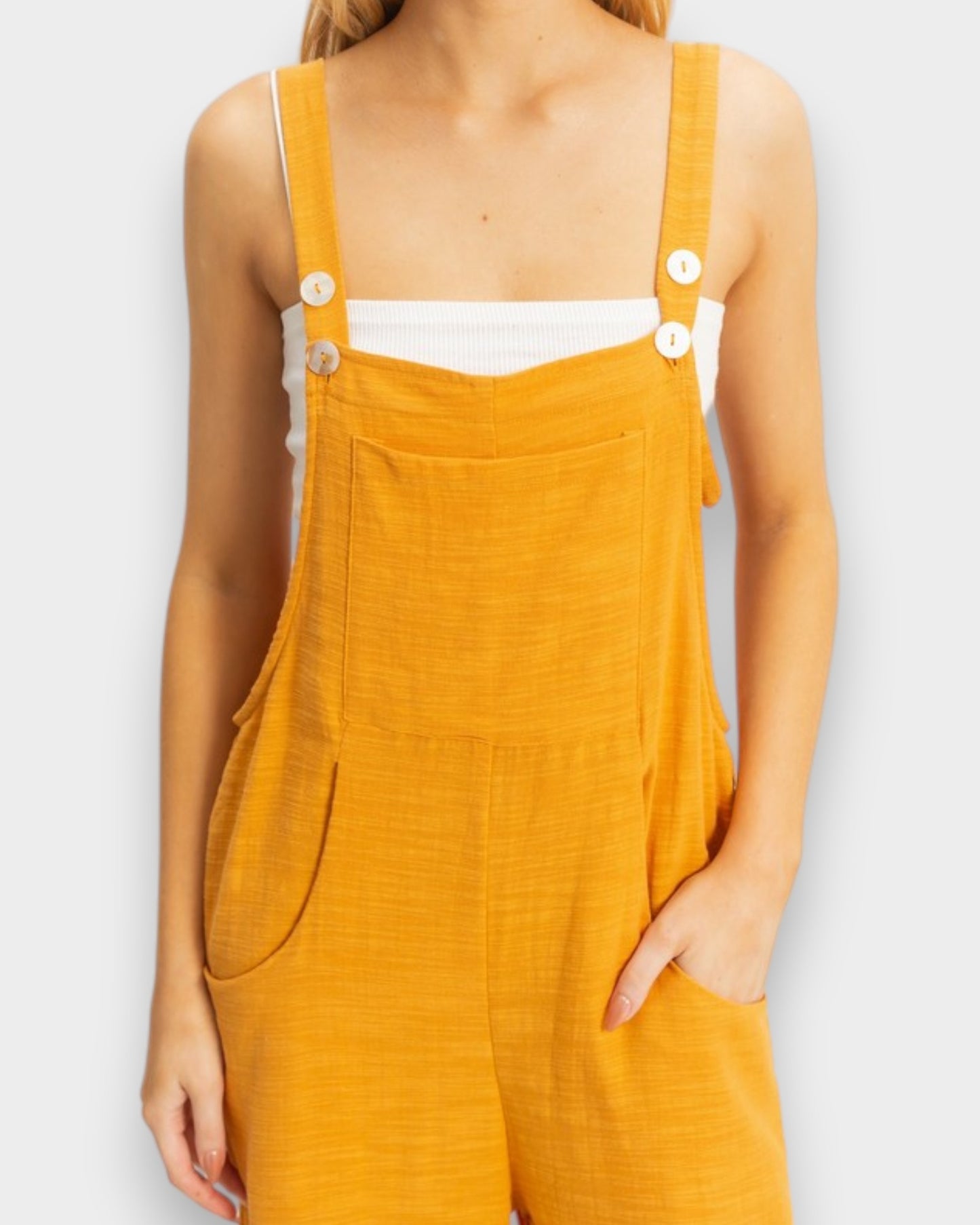 Yellow overalls worn by a person on a plain background