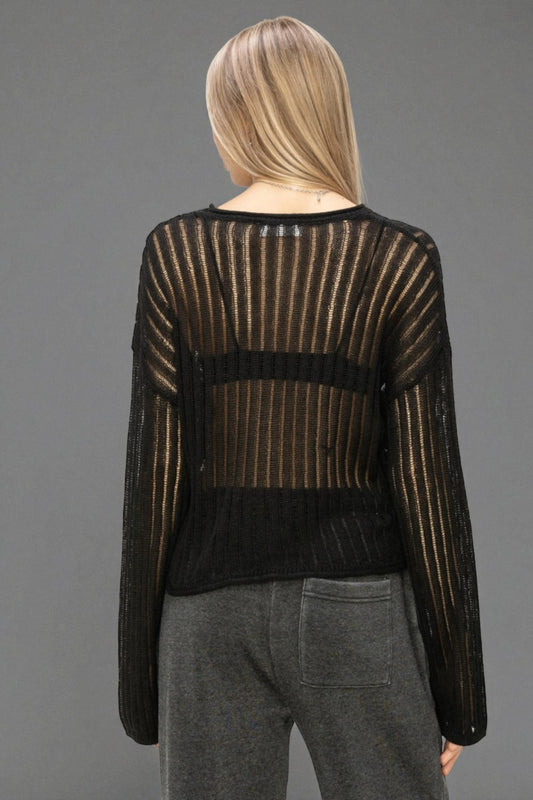 Person wearing a black and gold striped sweater with sheer panels on a gray background