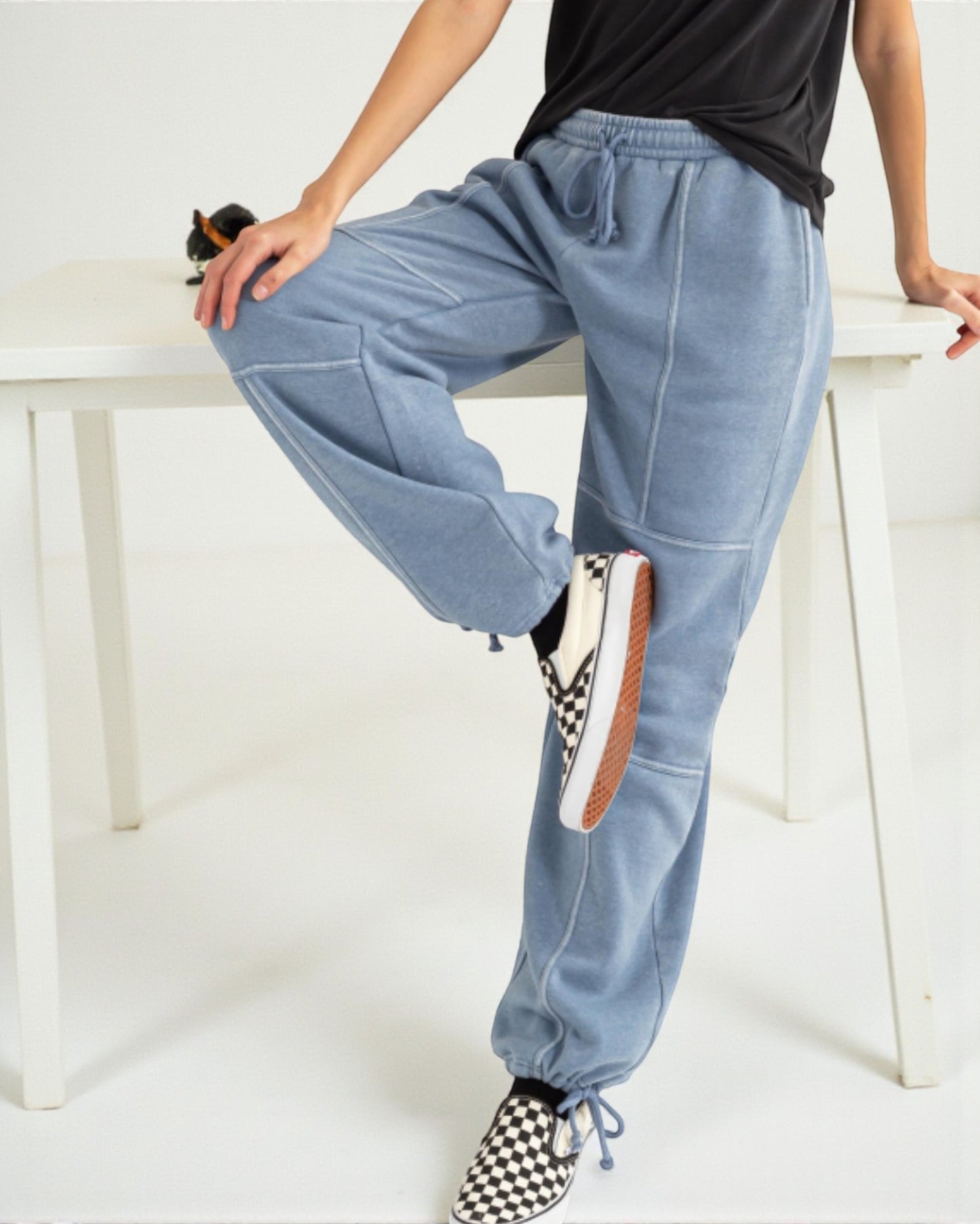 Person wearing light blue jogger pants sitting on a white bench.