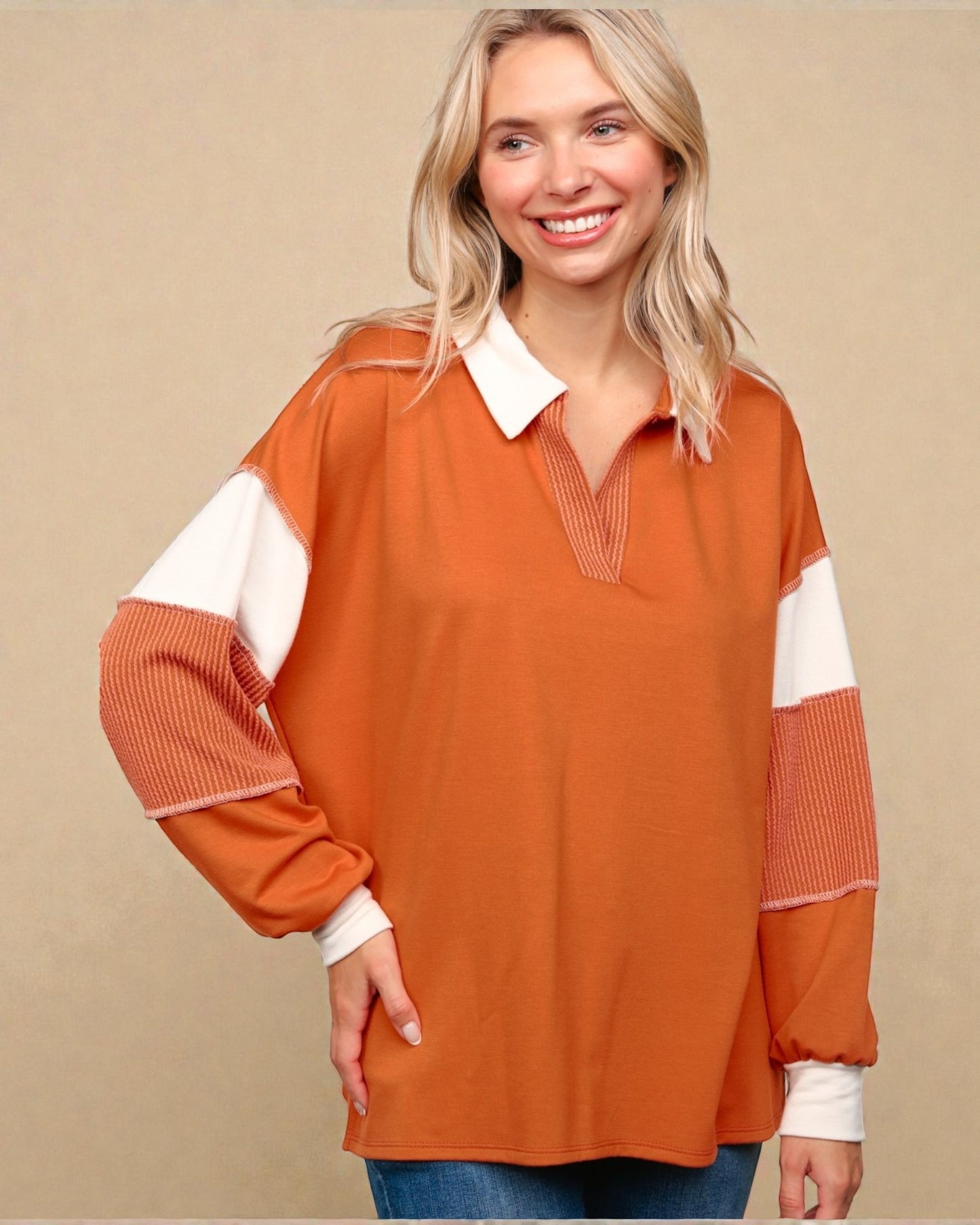 Woman wearing an orange and white long-sleeve top against a beige background
