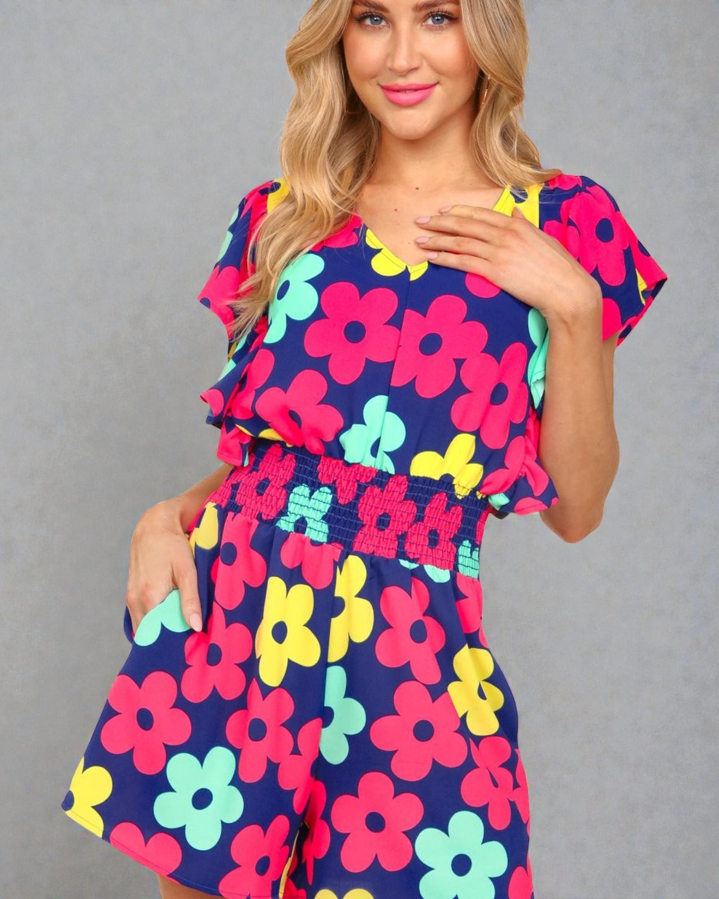 Woman wearing a colorful floral dress against a gray background