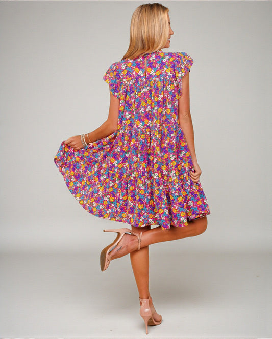 Woman wearing a colorful floral dress on a plain background