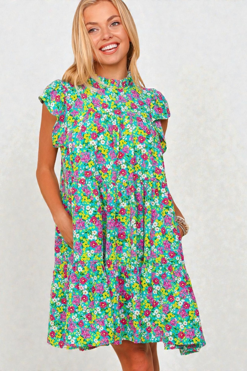 Woman wearing a colorful floral dress against a plain background