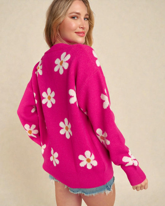 Woman wearing a pink sweater with white floral patterns on a beige background
