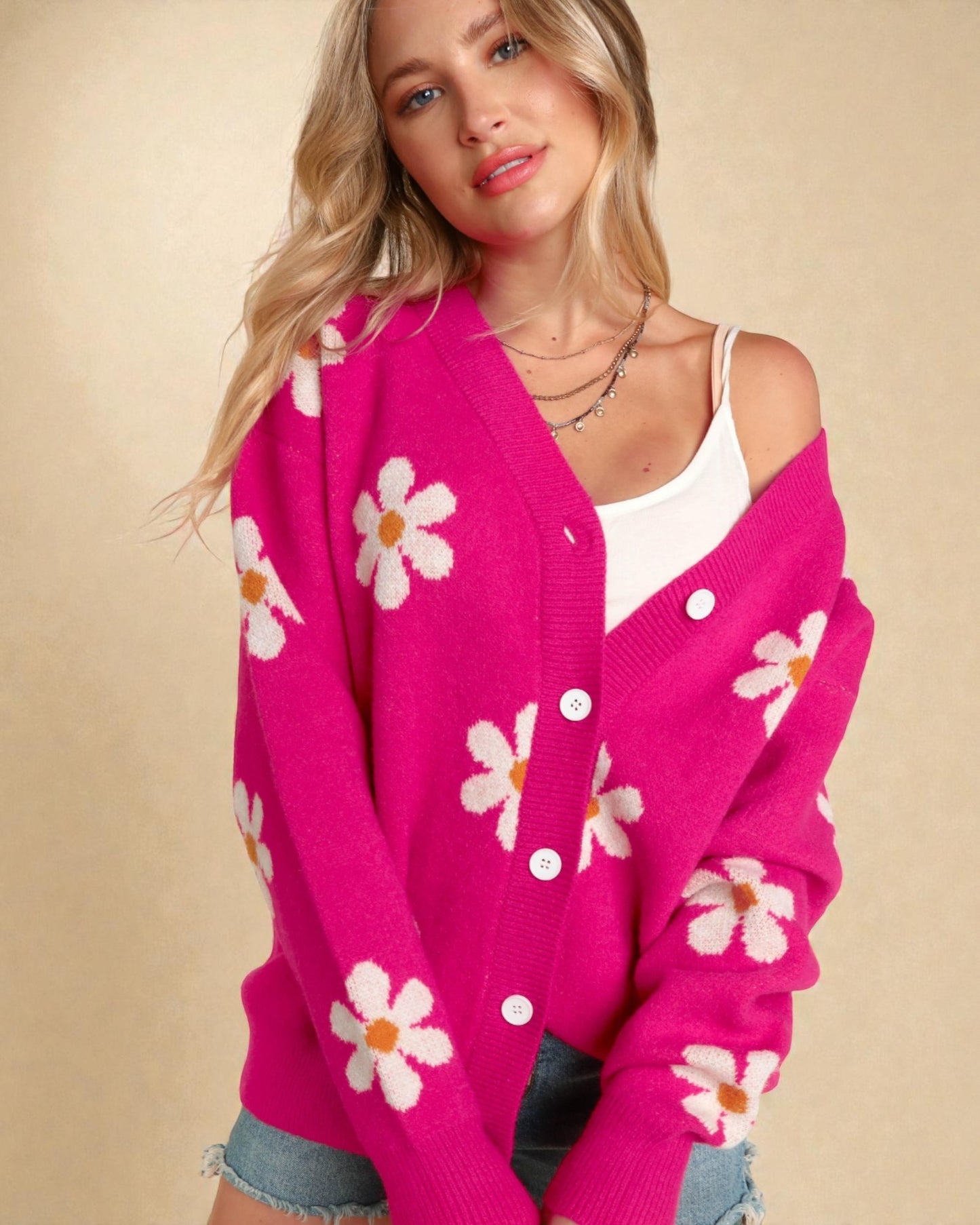 Woman wearing a pink cardigan with floral patterns on a beige background