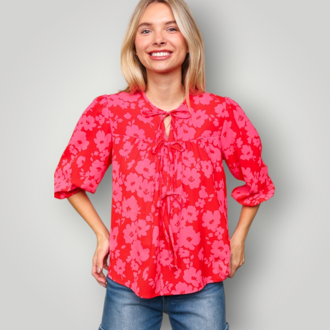 Woman wearing a red floral blouse against a gray background