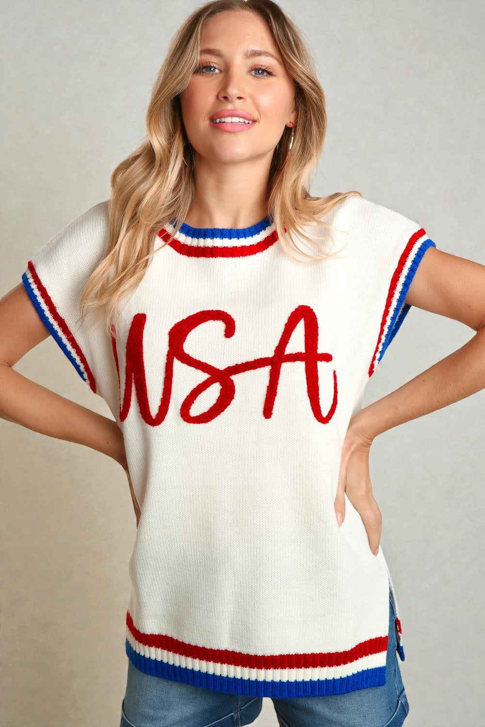 Woman wearing a white sweater with 'USA' printed in red, blue, and white on a neutral background