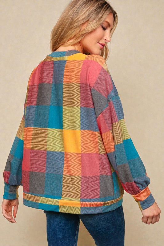 Woman wearing a colorful plaid sweater against a beige background