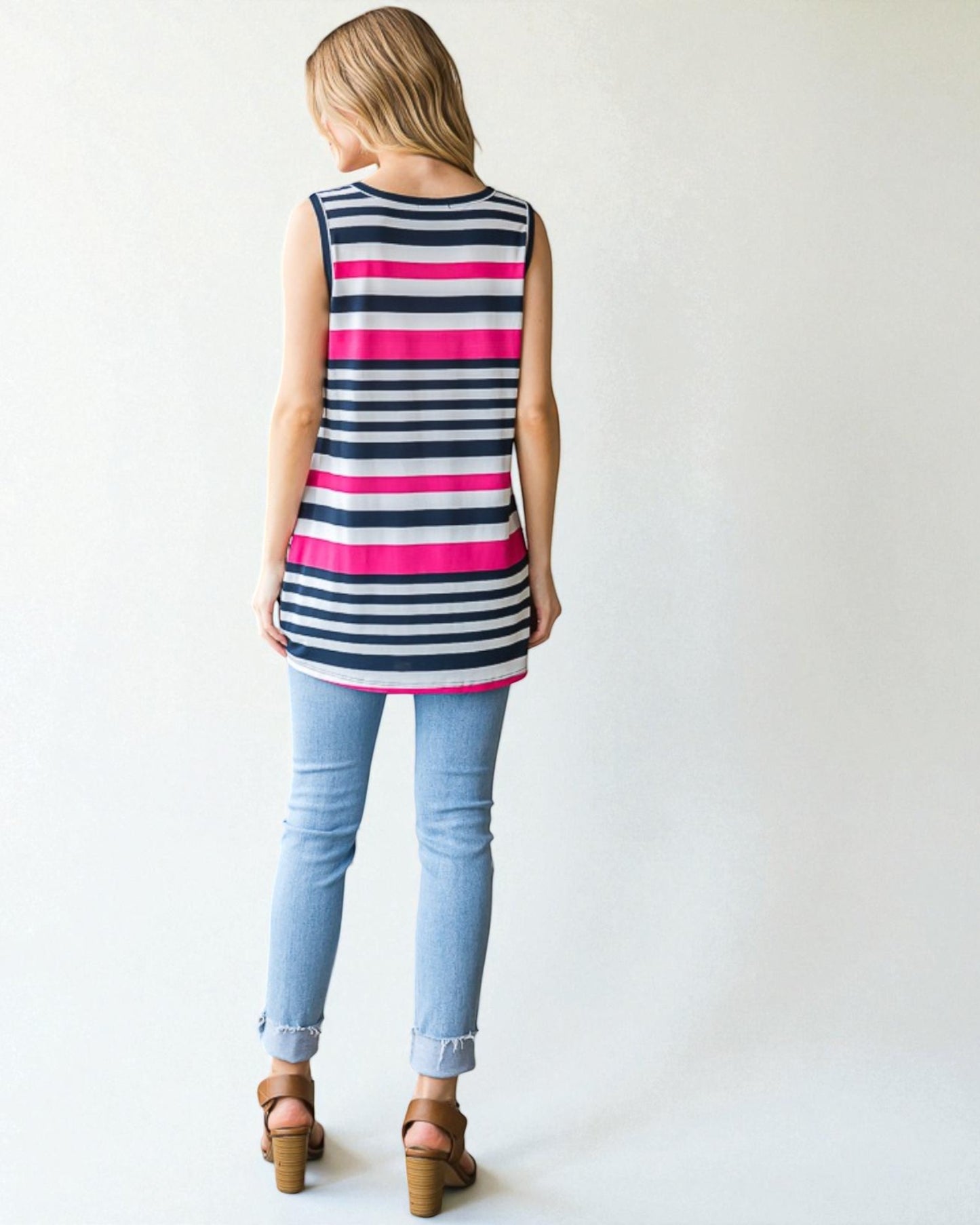 Woman wearing a sleeveless striped shirt and light blue jeans on a white background