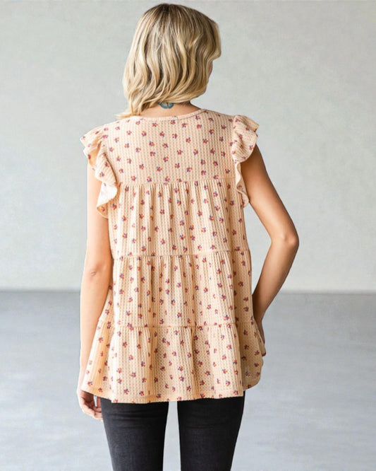 Woman wearing a beige floral blouse against a plain background
