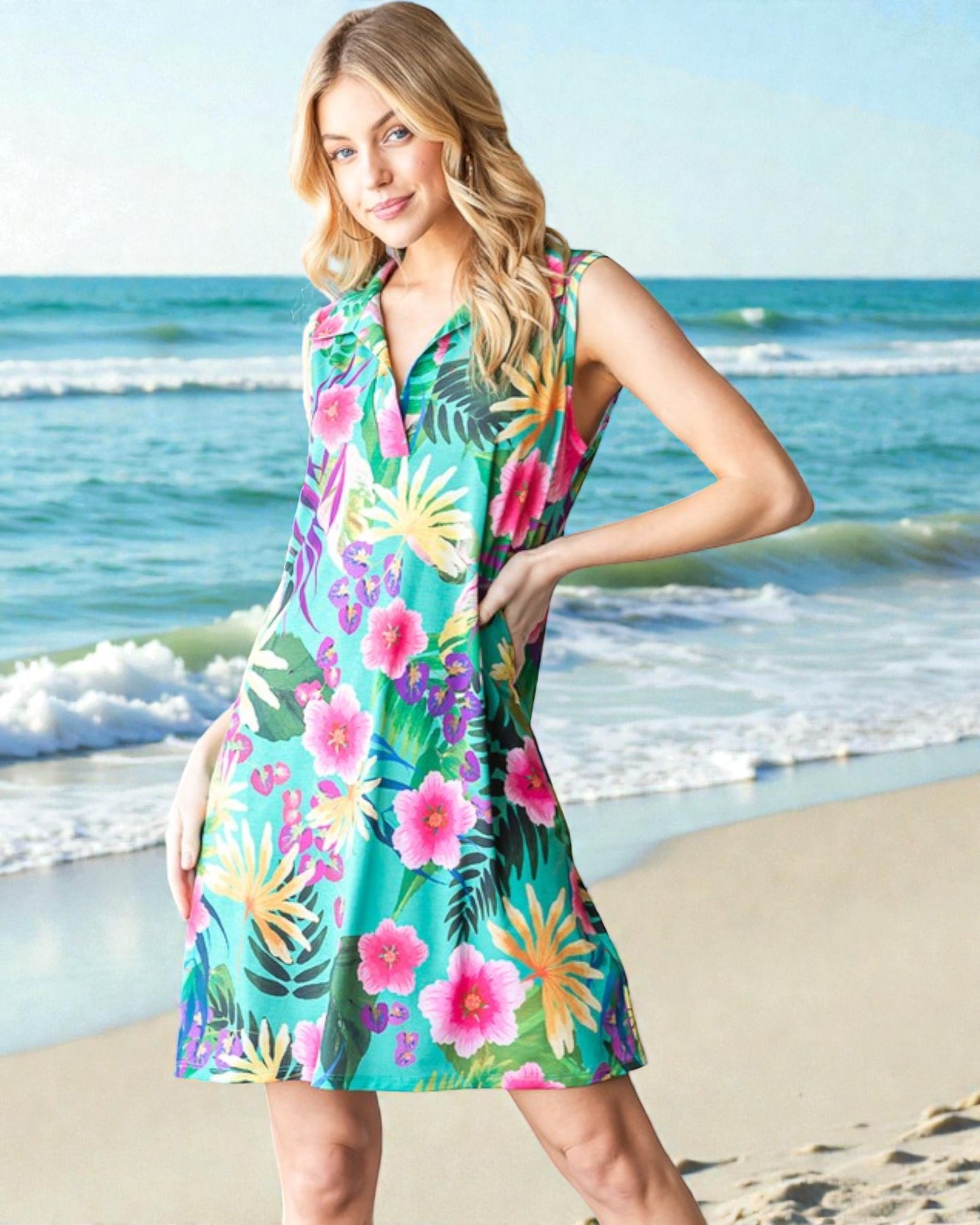 Woman wearing a colorful floral dress on a beach with ocean waves in the background