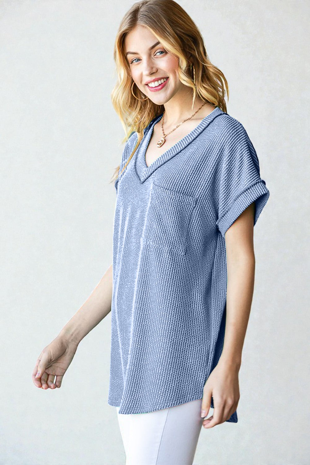 Woman wearing a blue textured top against a plain background