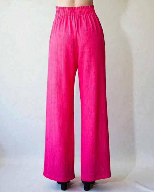 Bright pink wide-leg pants on a plain background