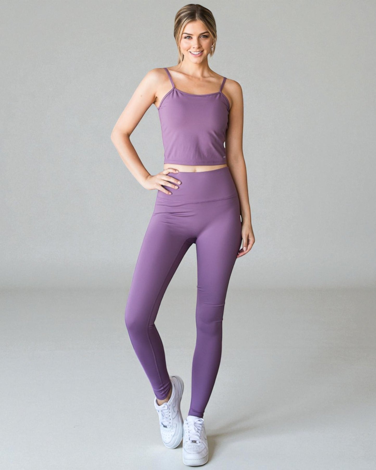 Woman wearing a purple athletic outfit on a gray background