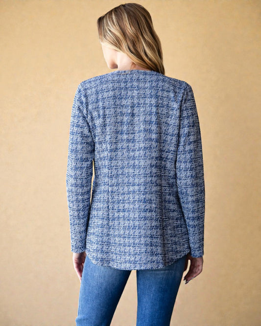 Person wearing a blue textured jacket against a beige background