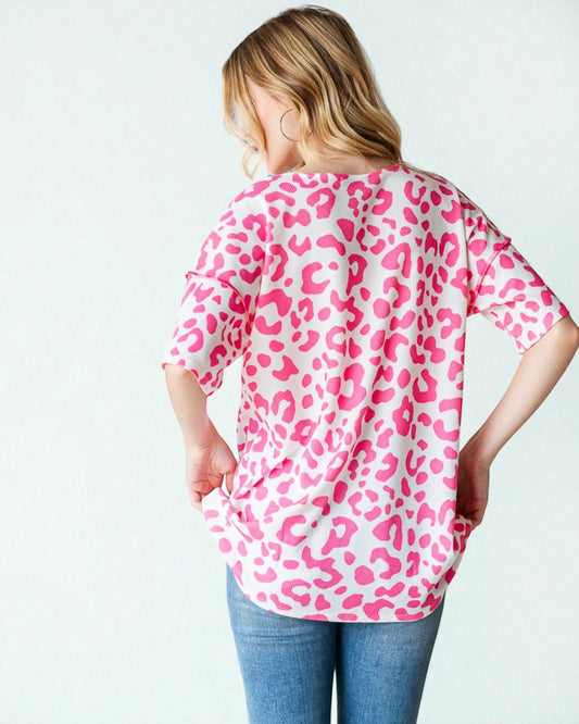 Person wearing a pink leopard print shirt on a white background