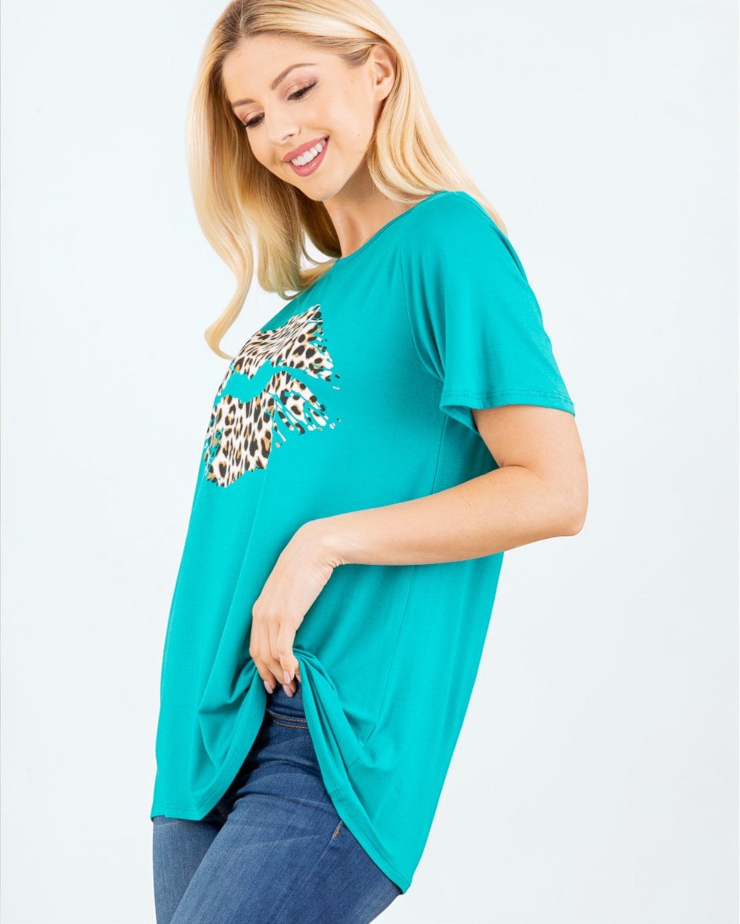 Woman wearing a teal t-shirt with a leopard print design on a white background