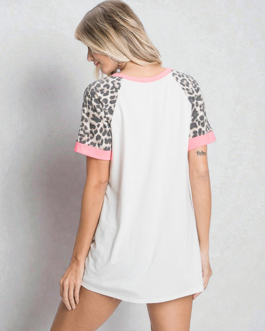 Woman wearing a white t-shirt with leopard print sleeves on a plain background