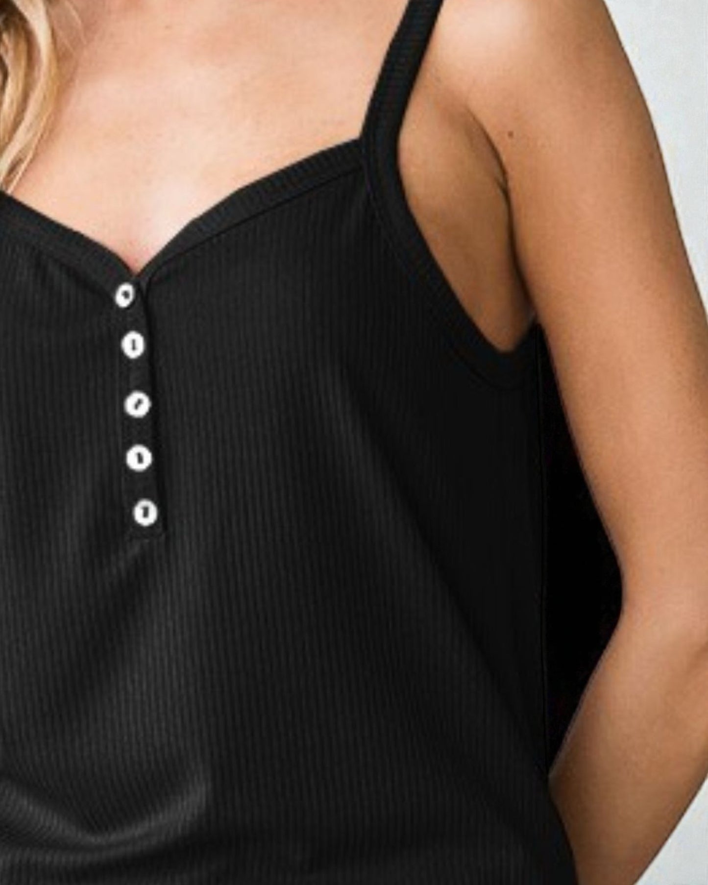 Black ribbed tank top with white buttons on a neutral background