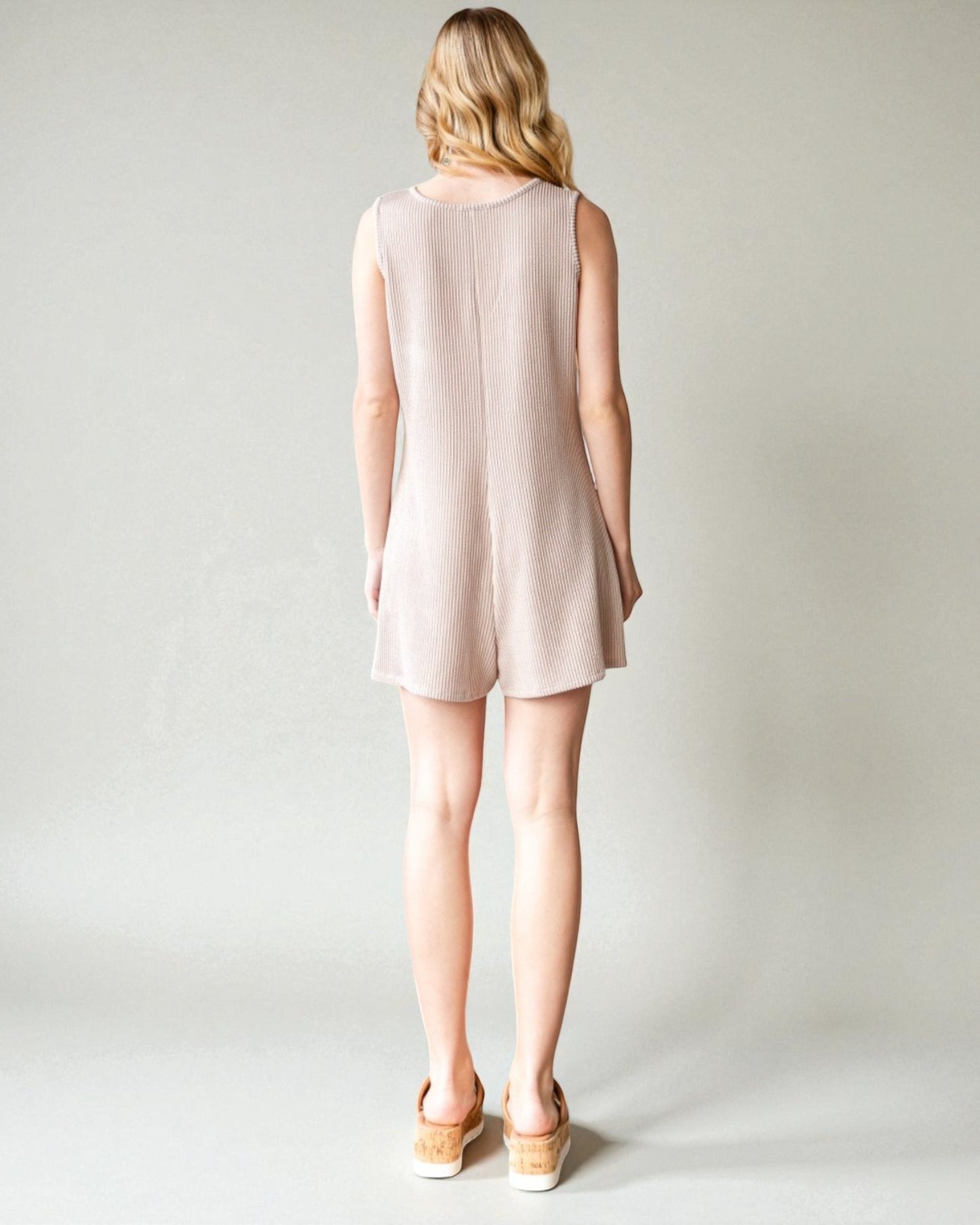 Woman wearing a light pink sleeveless dress on a plain background