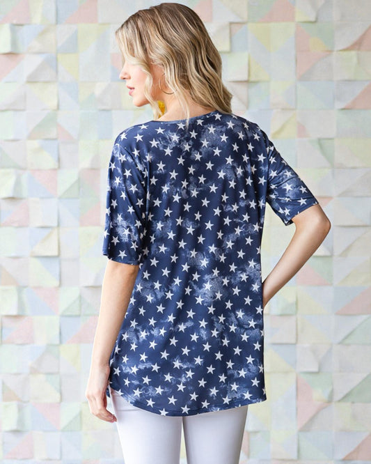Woman wearing a navy blue shirt with white star pattern against a geometric wall.