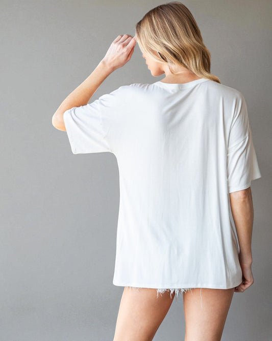 Person wearing a white oversized t-shirt against a gray background
