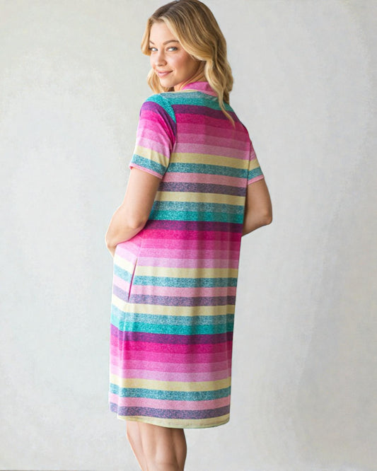 Woman wearing a colorful striped dress against a plain background