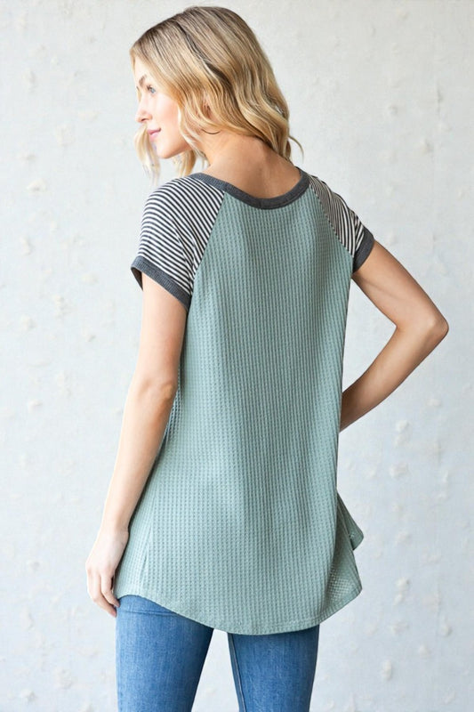 Woman wearing a green and gray striped shirt against a light background