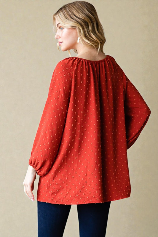 Woman wearing a red blouse with long sleeves on a beige background