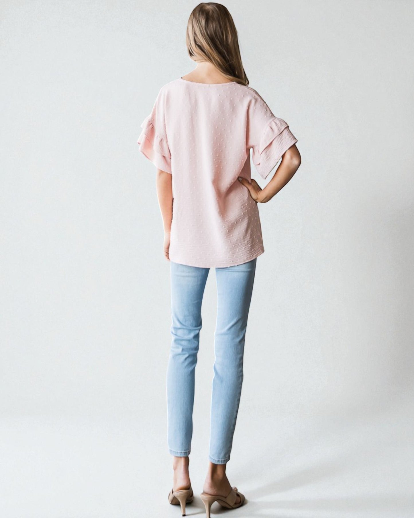 Person wearing a light pink blouse and light blue jeans on a white background