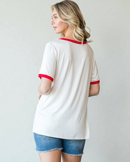 Woman wearing a white t-shirt with red trim and denim shorts on a plain background
