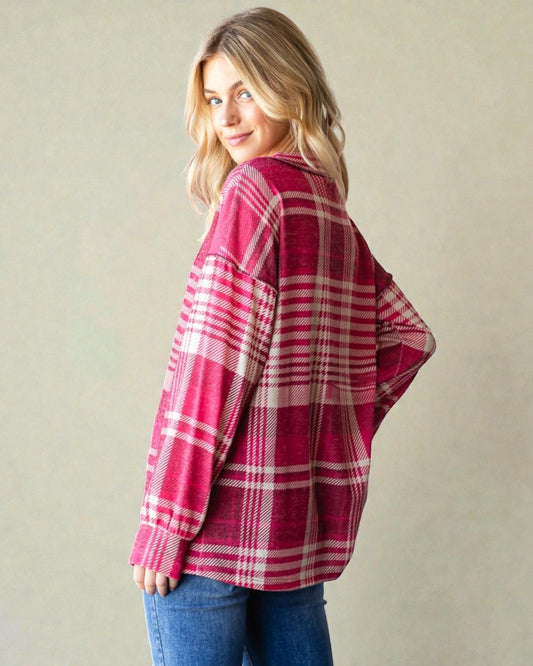 Woman wearing a red plaid poncho against a beige background
