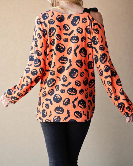 Person wearing an orange long-sleeve shirt with black Halloween pattern on a beige background