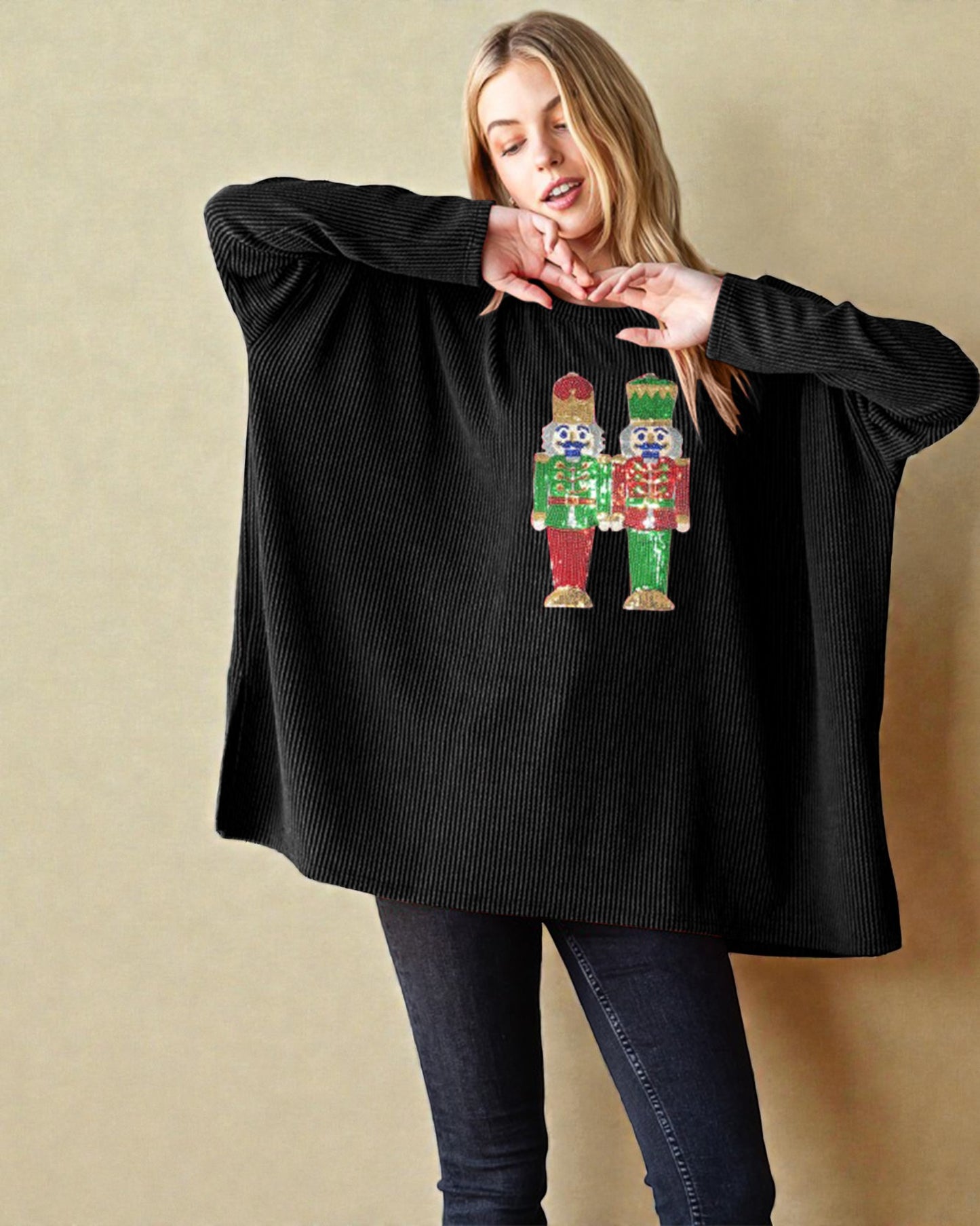 Woman wearing a black oversized sweater with a nutcracker design on a beige background
