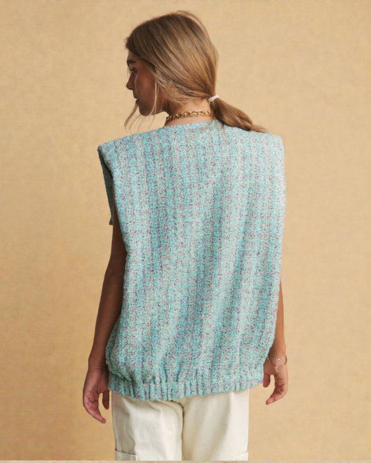 Woman wearing a light blue knitted vest against a beige background